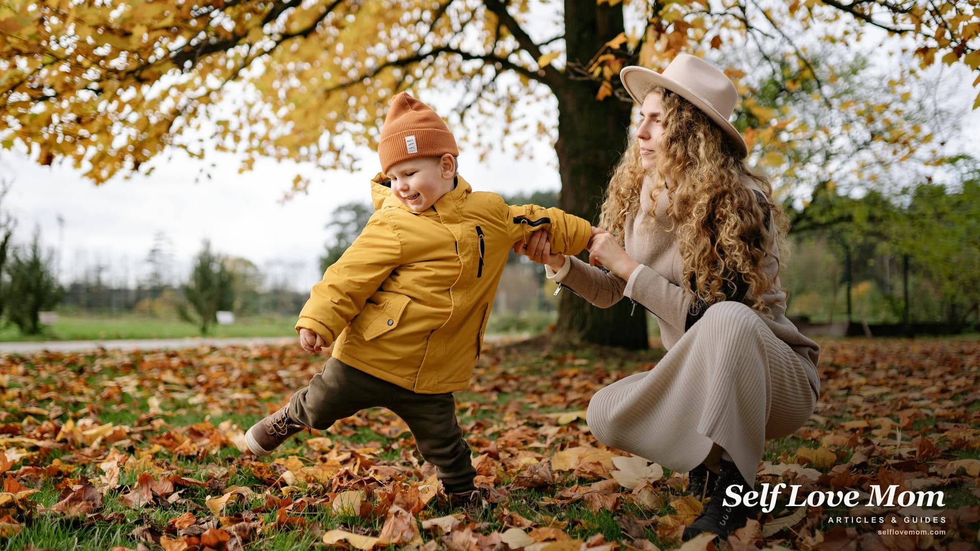 A mother and her young son laughing together in a sunlit autumn park, the kind of everyday moment single moms in NC work to protect through every grant they apply for.