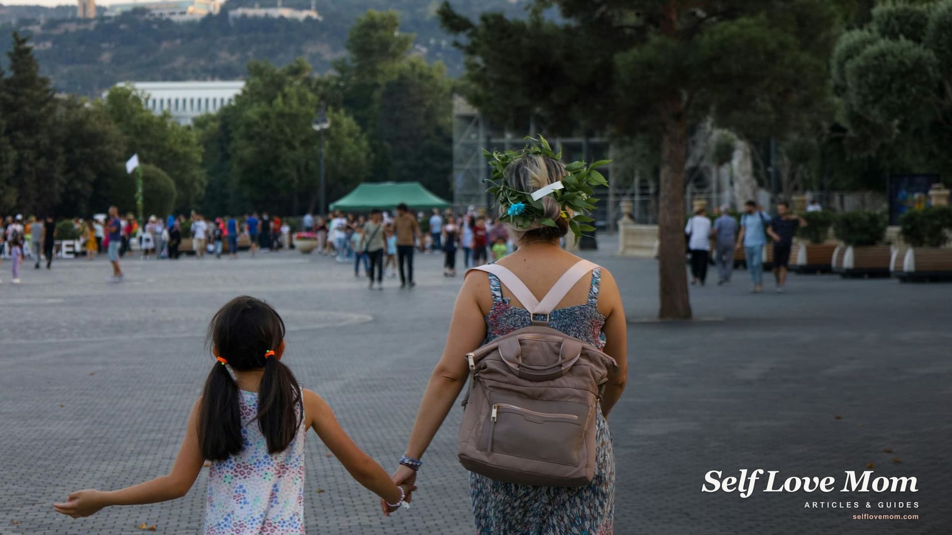 Rear view of a mother and her young daughter walking together hand in hand through a sunlit park, illustrating gentle co-parenting after separation.