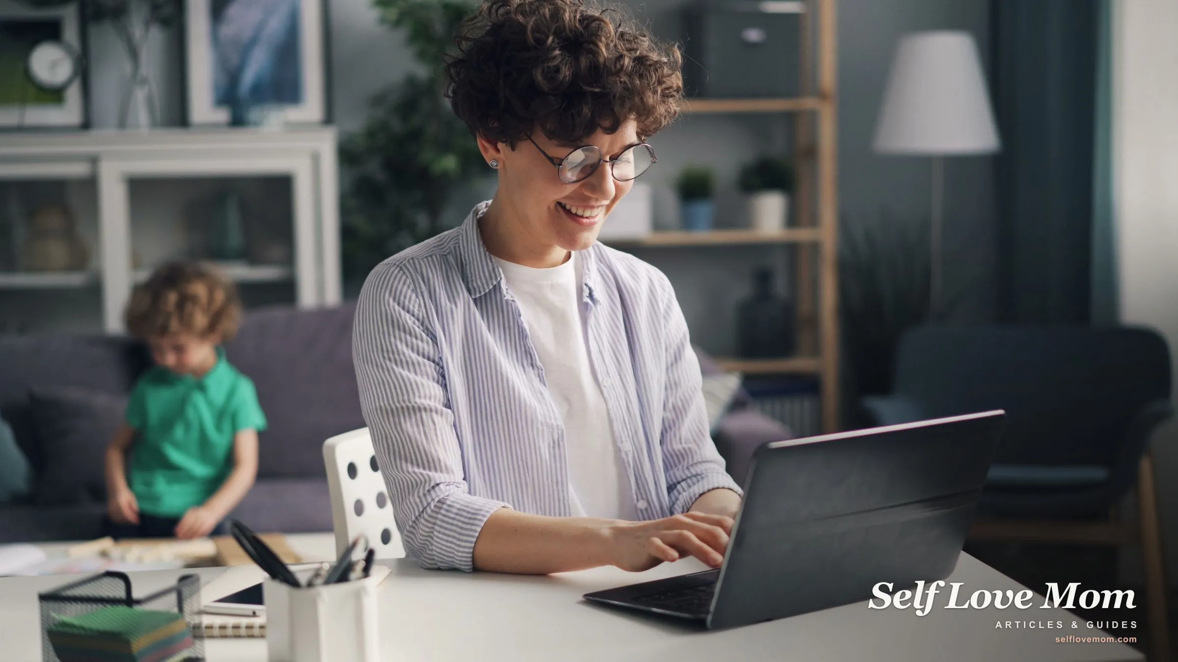 A single mom works on her monthly budget at a laptop while her child plays nearby at home.