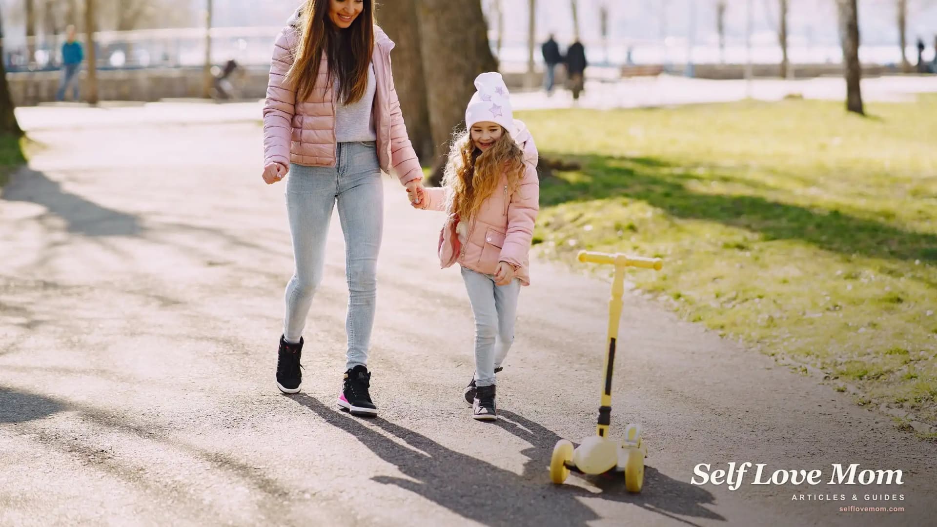 A single mom and her young daughter walk hand in hand through a sunny park, the steady, hopeful rhythm of surviving single-mom life.
