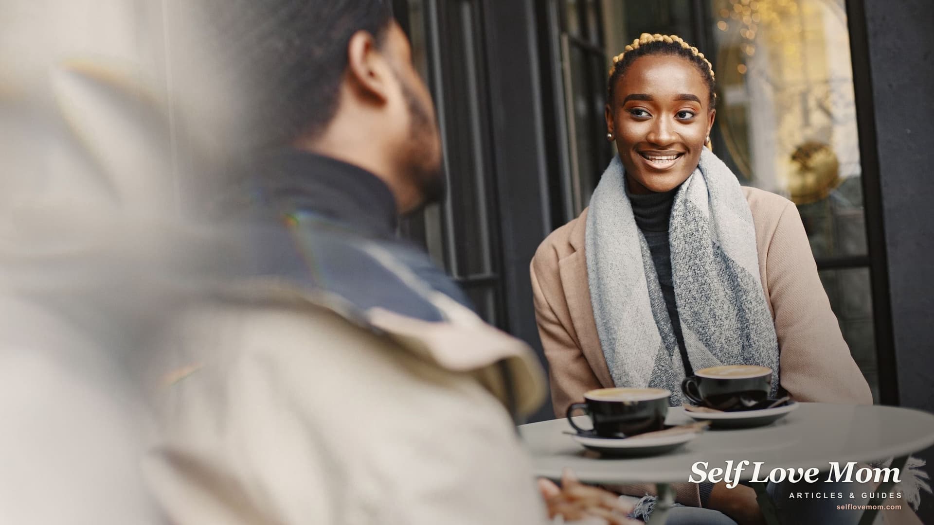 A woman smiling across an outdoor cafe table on a first coffee date, the kind of low stakes public meeting most dating advice for single moms recommends.