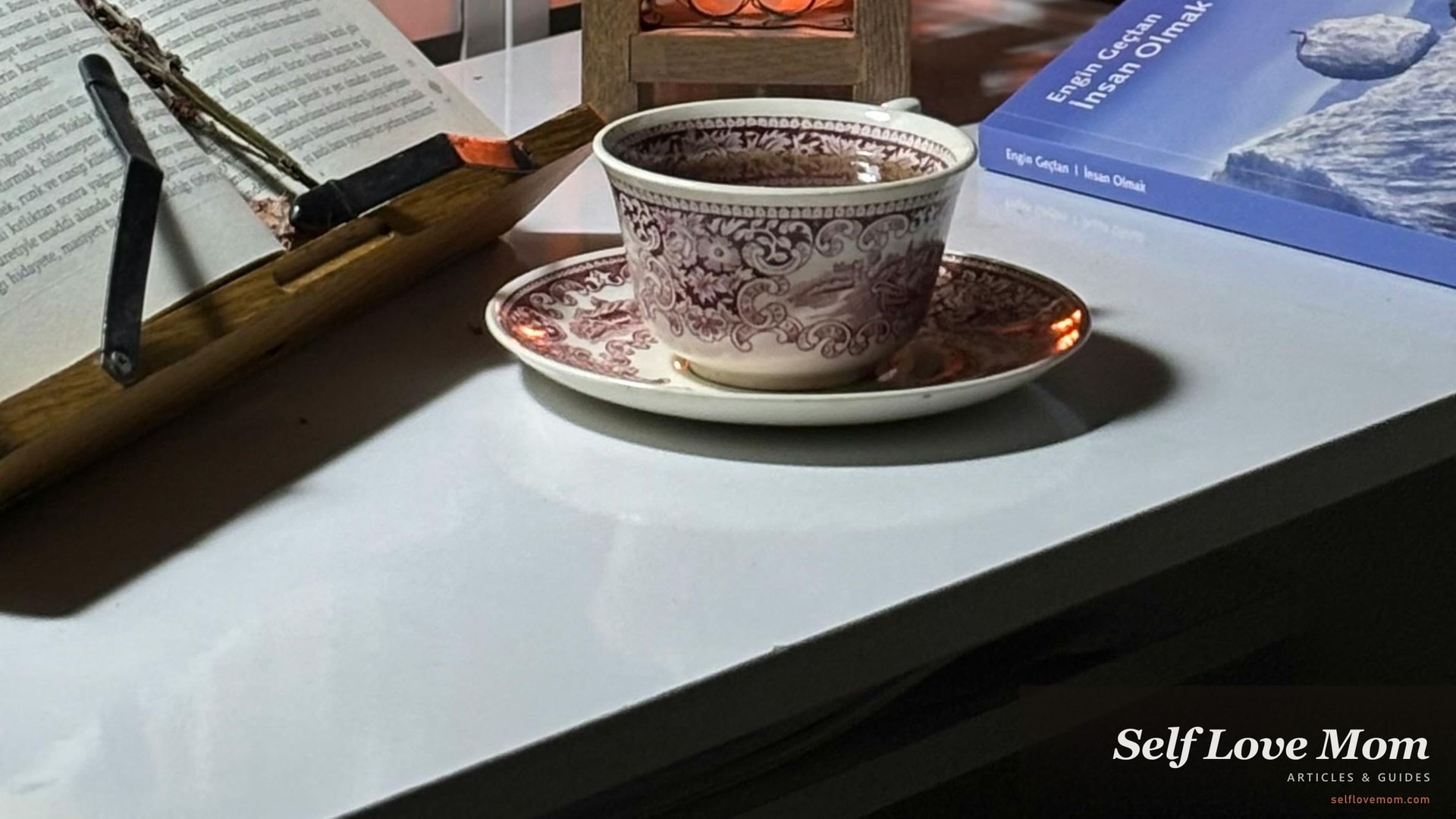 A cozy reading nook with a steaming mug of tea, lit candle, and an open book in warm evening light. Self-care night for single moms.