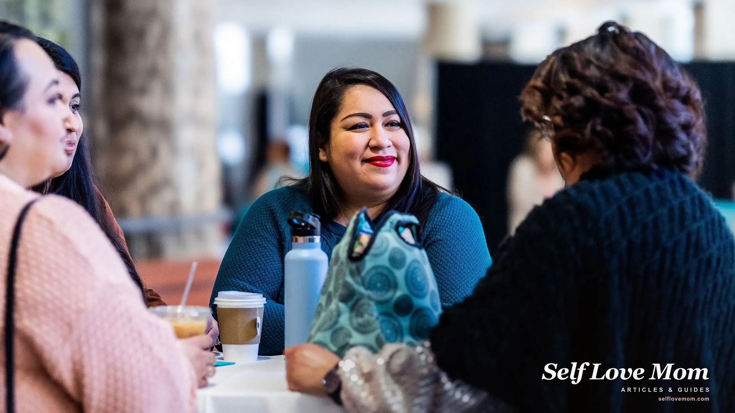 A small group of women talk and share support over coffee at a community meetup.