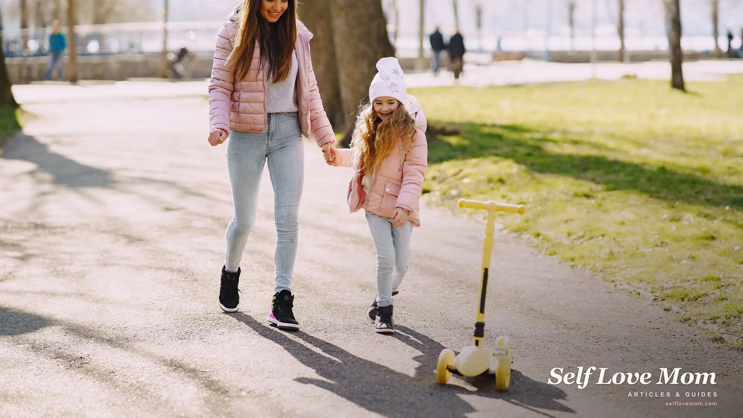 A single mom and her young daughter walk hand in hand through a sunny park, the steady, hopeful rhythm of surviving single-mom life.