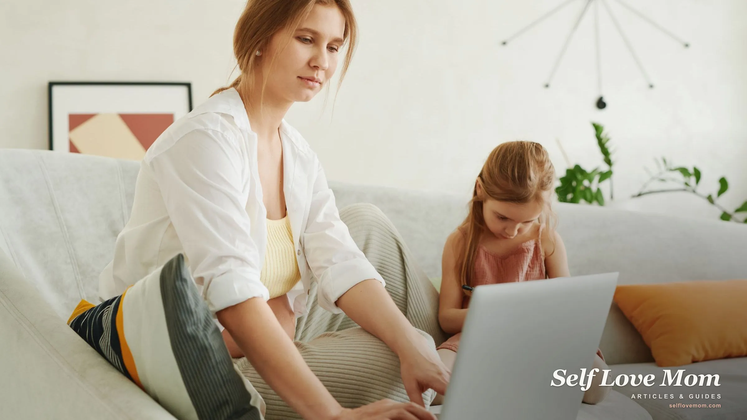 A single mom works on her laptop with her young daughter beside her on the couch, planning the family's debt payoff at home.