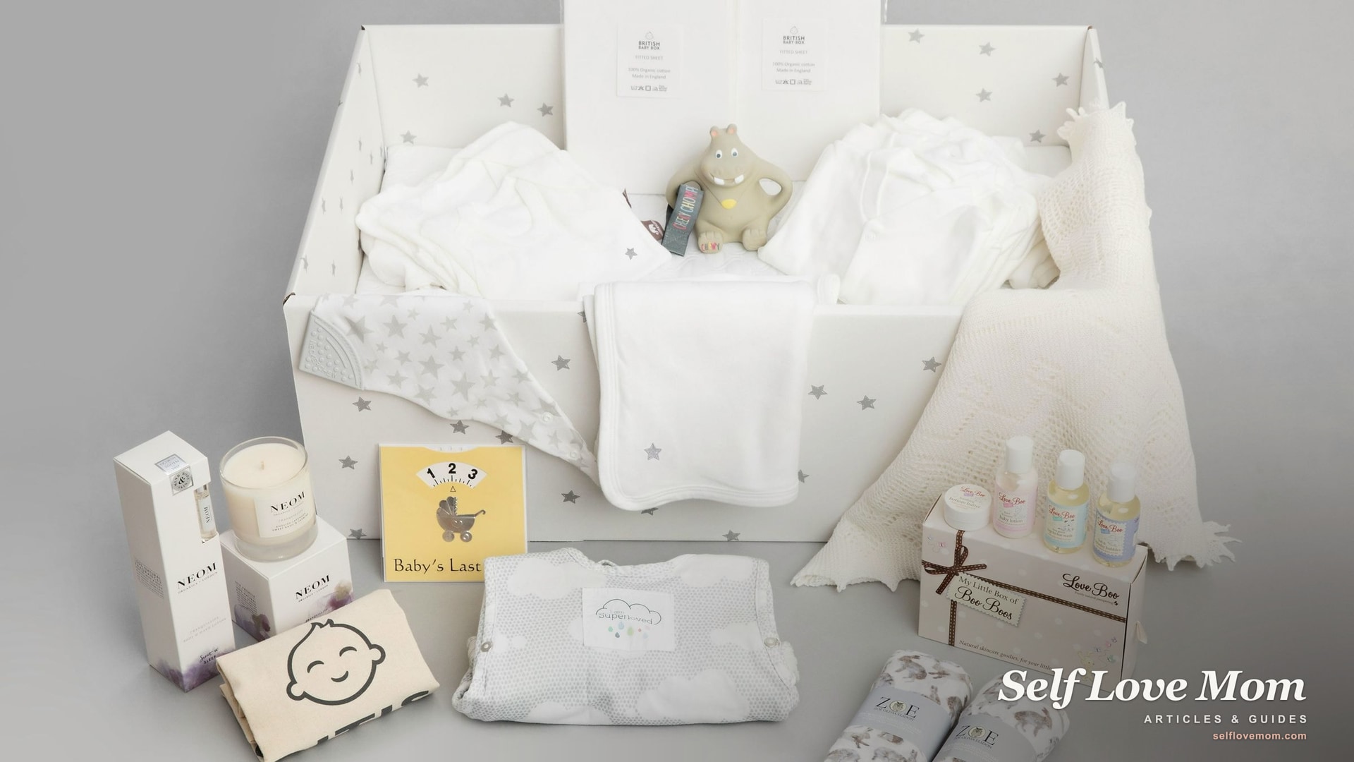 A neutral-toned gift hamper for a new mom with its contents laid out on a table, the kind of care package that says someone is thinking of her.