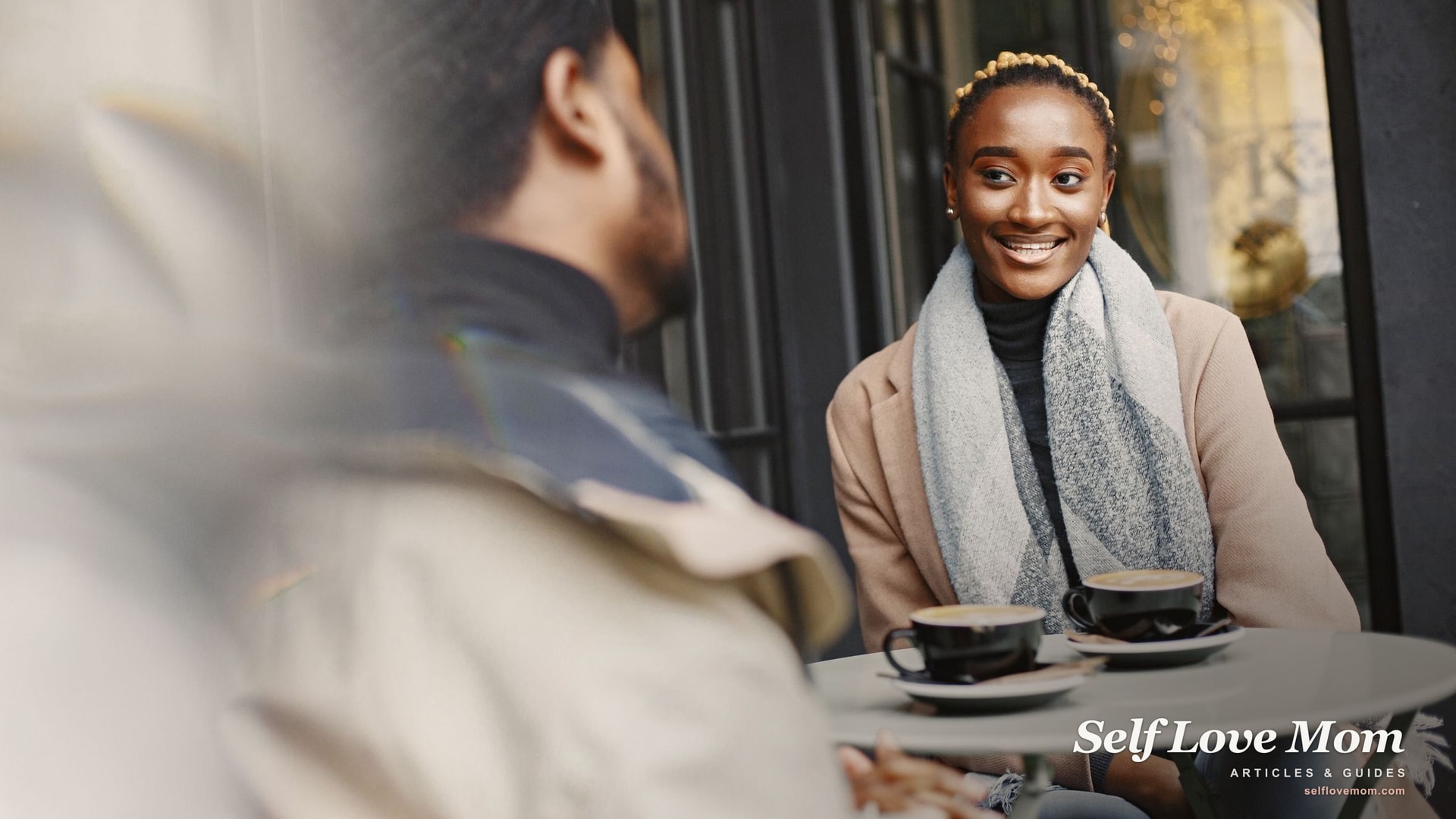A woman smiling across an outdoor cafe table on a first coffee date, the kind of low stakes public meeting most dating advice for single moms recommends.