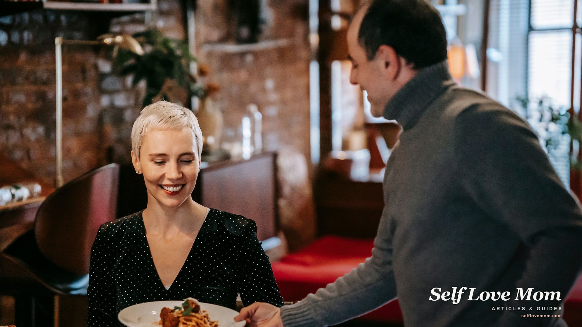 A woman smiling at a dinner date as her partner serves pasta, the low-pressure reality of dating after divorce.