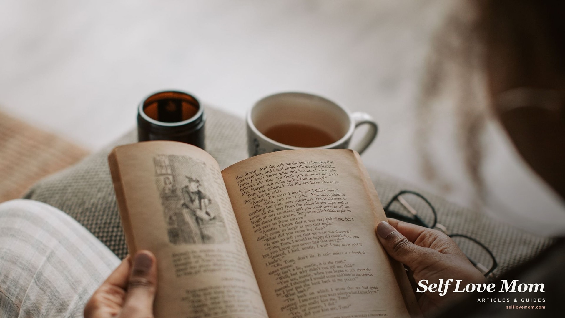 An open book, a lit candle, and a cup of tea on a soft blanket, the calm a good relaxation gift creates for a stressed mom.