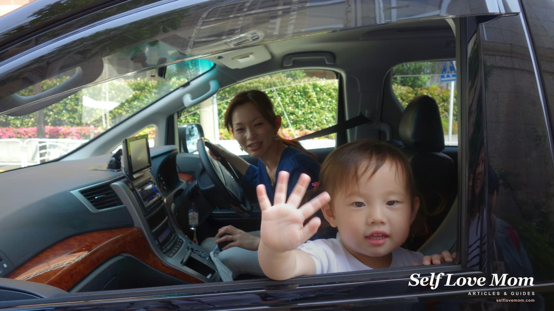 A single mother sits in the driver seat as her young child waves from the passenger window, the small everyday outcome of a donated-car program that connects working single moms with reliable transportation.