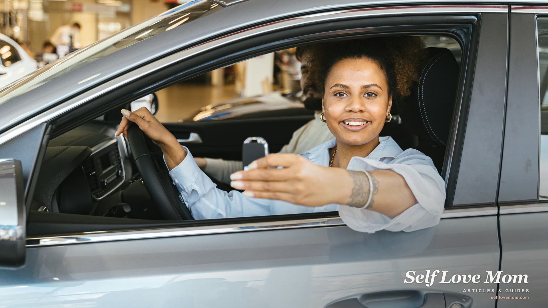 A smiling single mother leans out of her car window holding the keys, the moment of receiving a free car from a nonprofit donation program changes daily life for a working single mom.