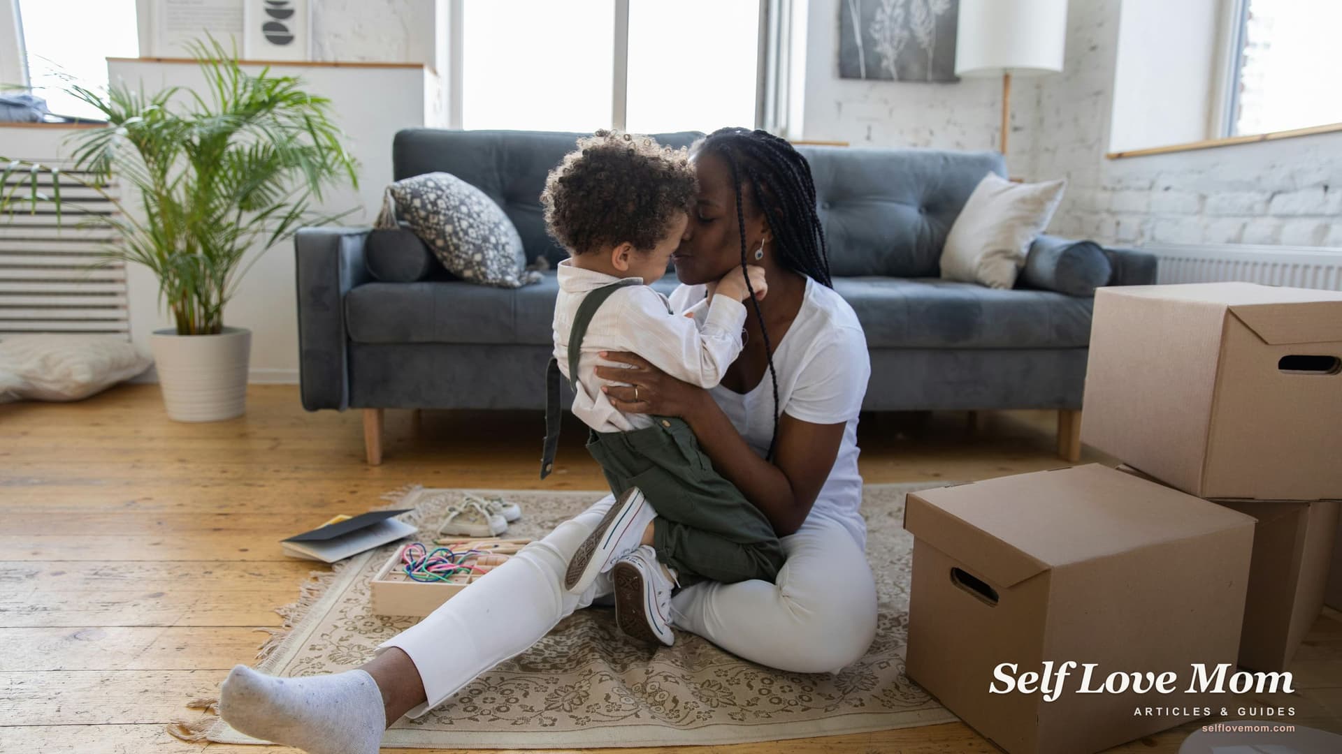 A single mom kisses her daughter as they unpack moving boxes in the first home she bought using buyer grant assistance