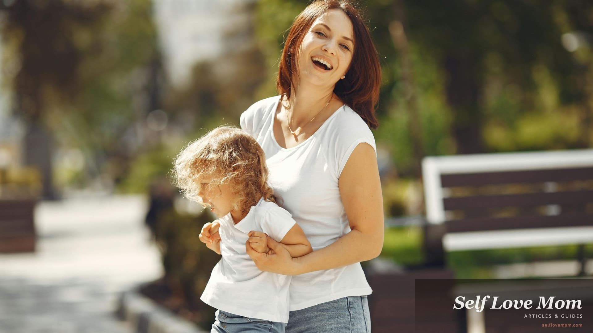 A single mom in Alabama carries her young daughter through a sunlit park, a quiet bonding moment behind the day-to-day costs Alabama's 8+ grant and aid programs in 2026, Family Assistance, SNAP, AHFA Step Up, child care subsidy, and ASAP, help cover.