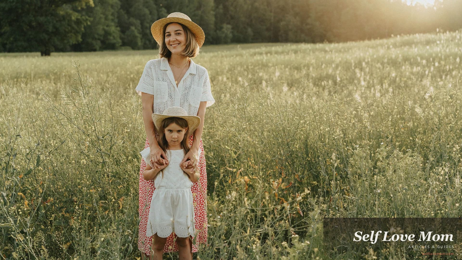 California single mom stands in a sunlit grass field with her young daughter, both wearing straw hats and smiling at the camera, the kind of grounded outdoor moment Cal Grants, CalWORKs, and CalFresh exist to protect while a parent rebuilds.