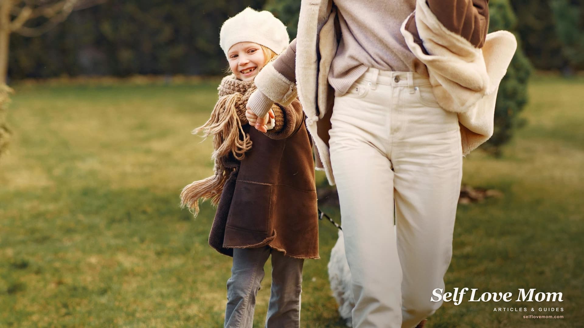 A mother and her young daughter running together through a sunny park, smiling, dressed in autumn colors.
