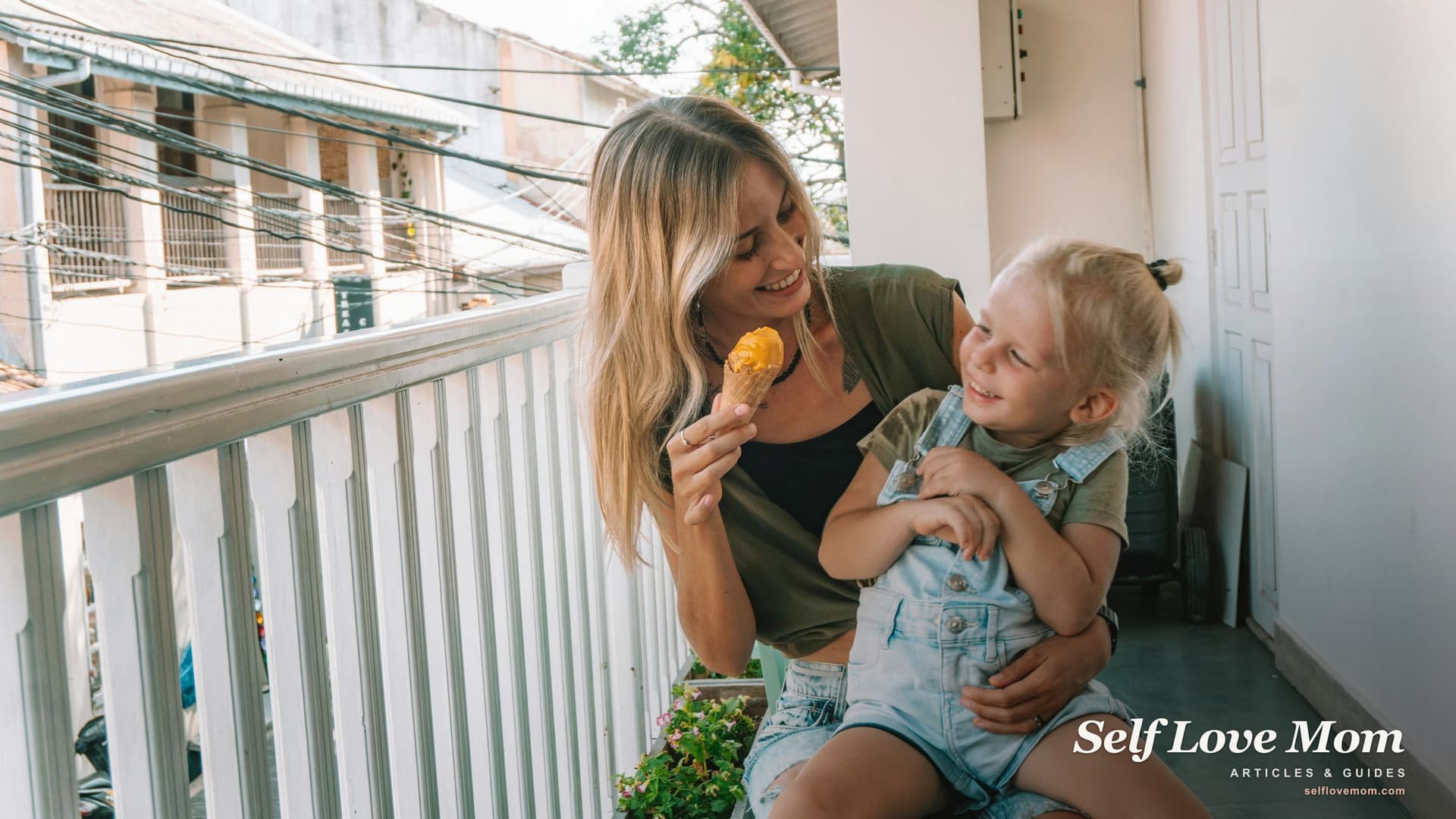 A mother and her daughter laughing together over ice cream on a sunlit balcony, the kind of small everyday moment single moms in Louisiana work to protect through every grant they apply for.