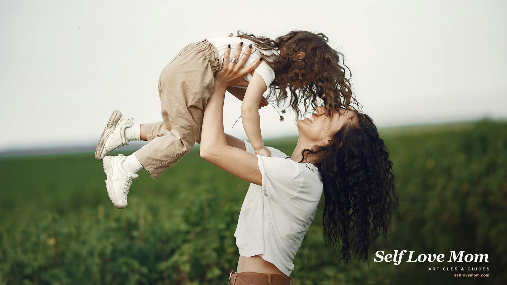 A mother lifting her young daughter playfully in a sunlit Midwestern field, the kind of joyful everyday moment single moms in Missouri work to protect through every grant they apply for.