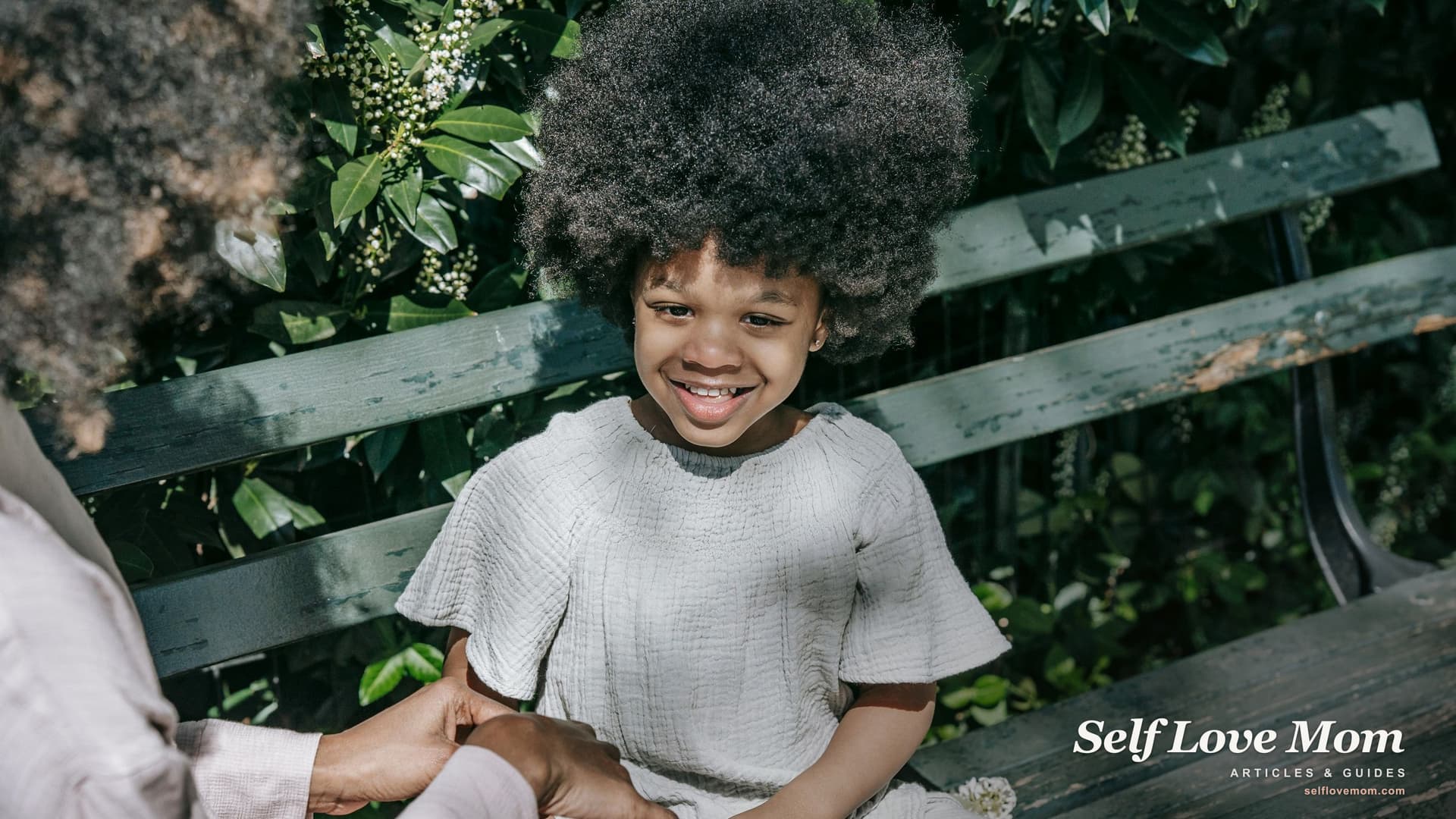 A mother and her daughter laughing together on a sunlit park bench, the kind of everyday moment single moms in SC work to protect through every grant they apply for.