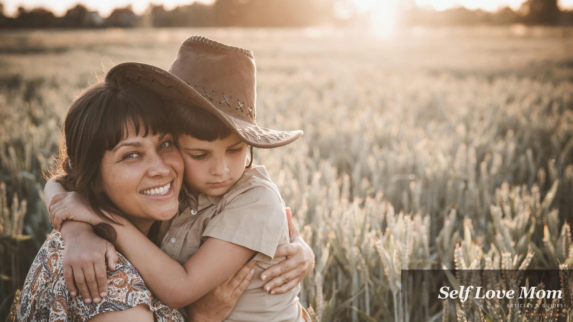 Single mother holding her young son close in a grassy outdoor field at golden hour, the kind of moment Oklahoma grants for single mothers are designed to support, by funding rent, food, childcare, and college costs so parenting feels less precarious.