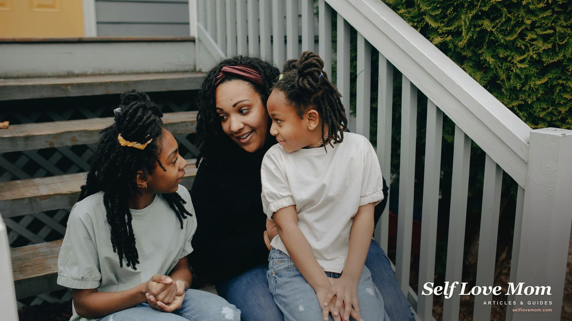 A single mom and her two daughters sit on the front porch steps of the home she just bought with an FHA loan