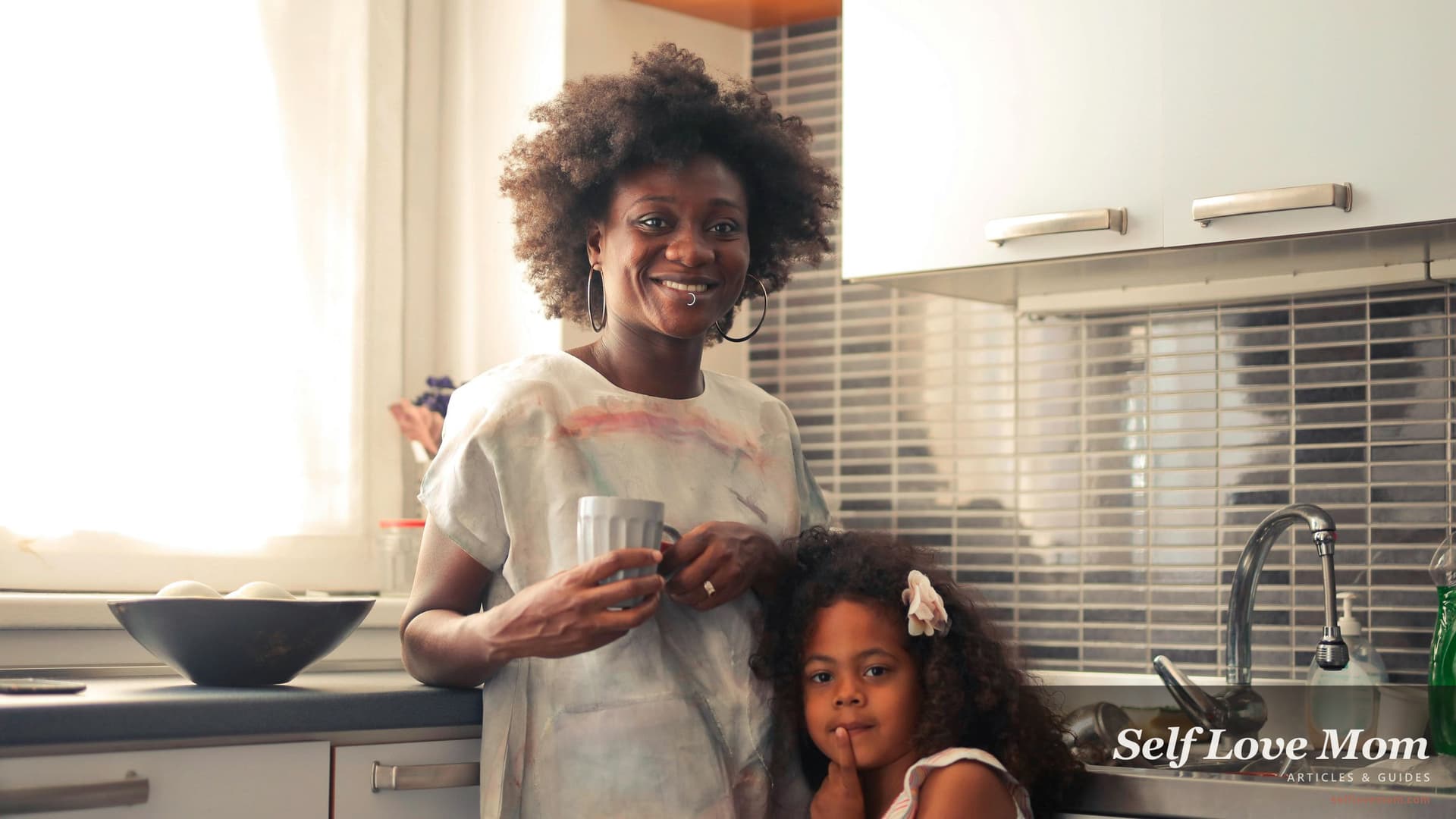 Single mom in Indiana standing in a warm morning-lit kitchen with her young daughter, mom smiling with a coffee mug, the kind of weekday-real moment that the seven Indiana benefits programs in this guide are built to support.