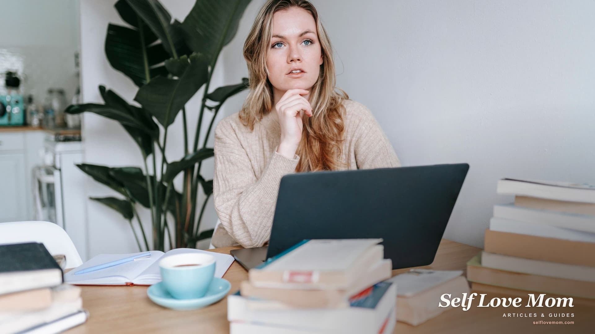 A focused woman sits at a laptop surrounded by books, planning a career path on one income.