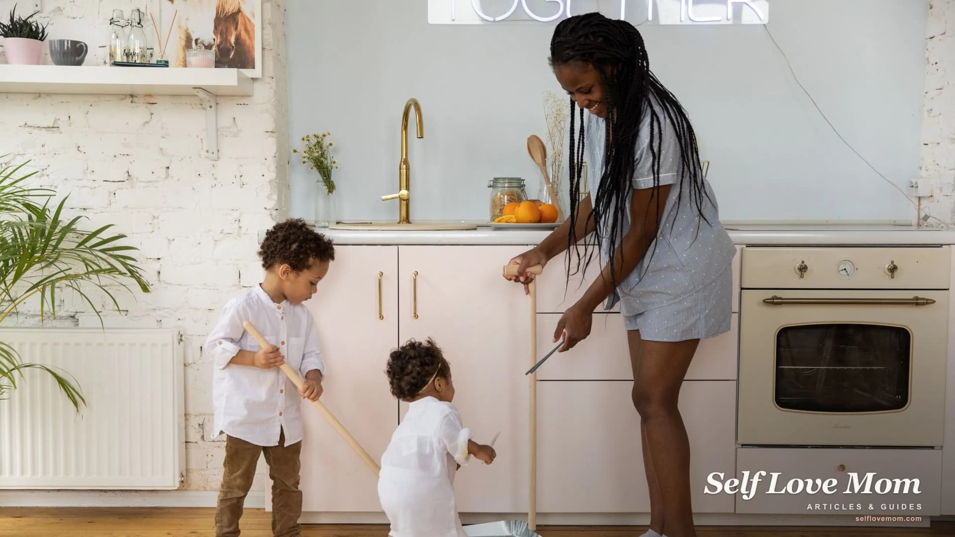 A mom and her two children sweep the kitchen together, sharing the cleaning as a family.