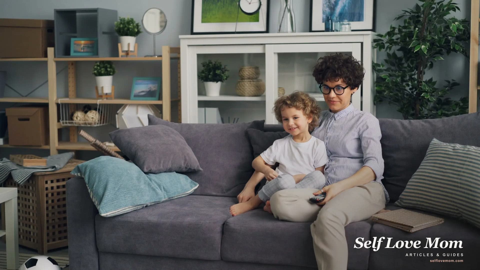 A mother and her young son relax on the living-room couch, the calm, steady home that protects a child through high conflict.