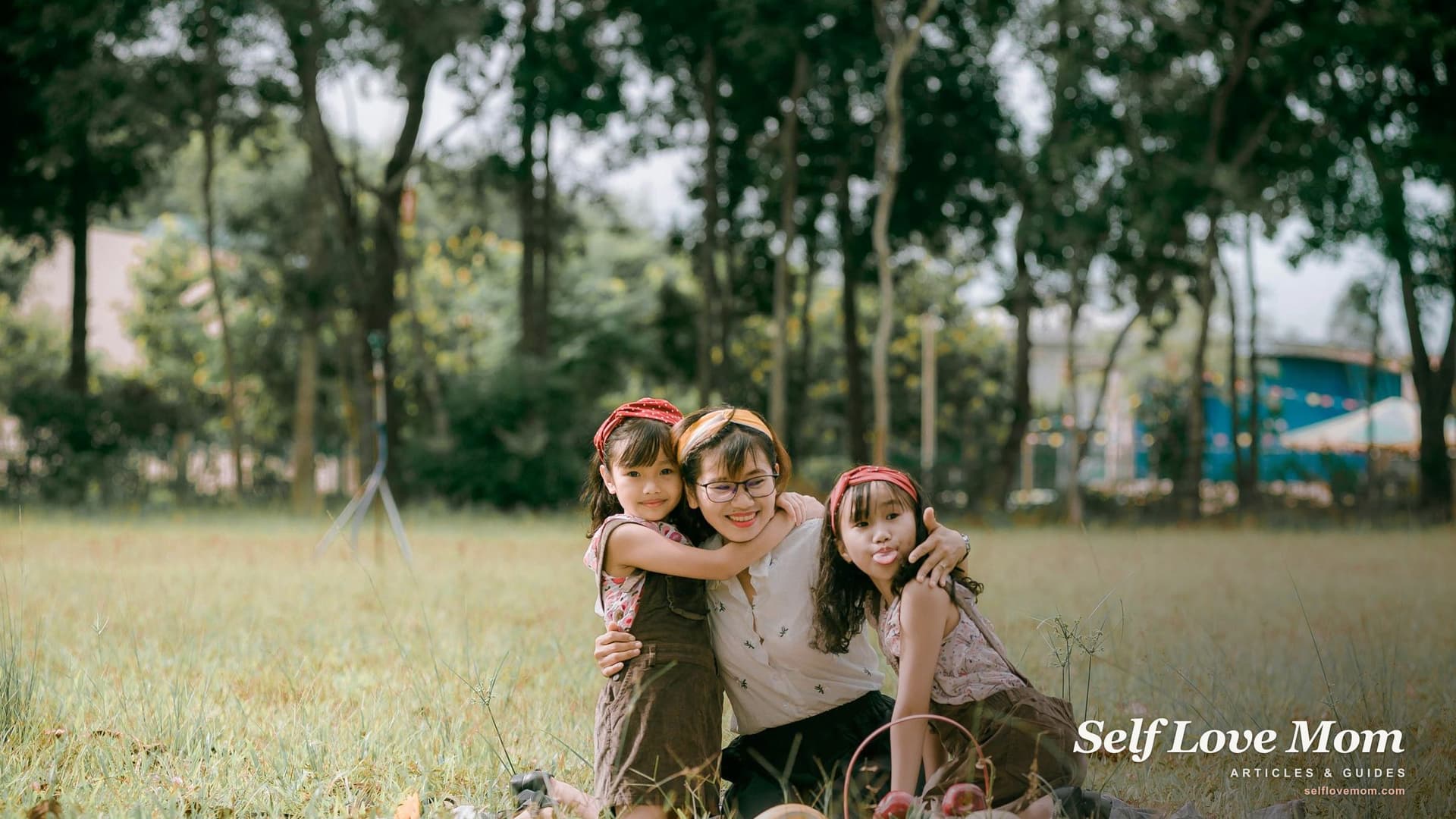 A single mom hugs her two daughters outdoors in a sunny park during the Memorial Day weekend