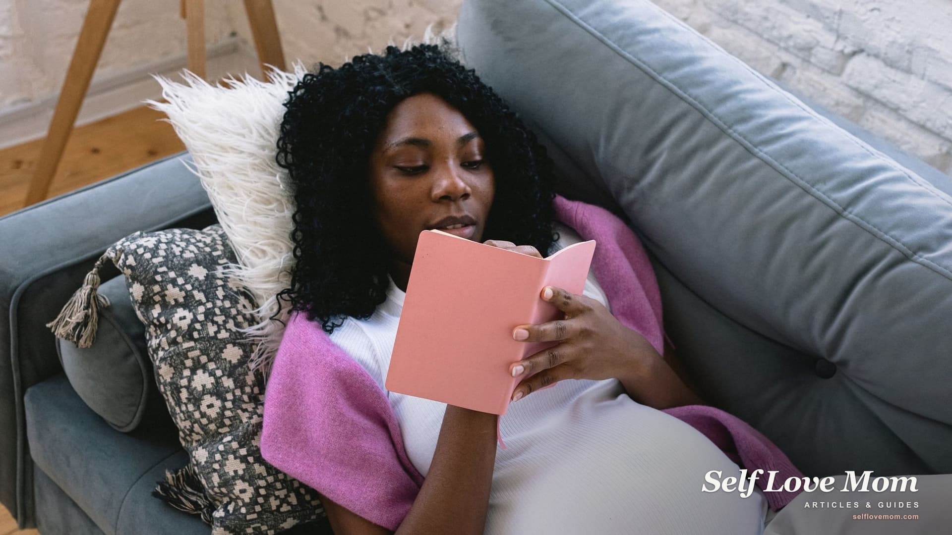 A pregnant woman reads and plans in her notebook at home, the kind of student scholarships for pregnant mothers help fund in 2026.