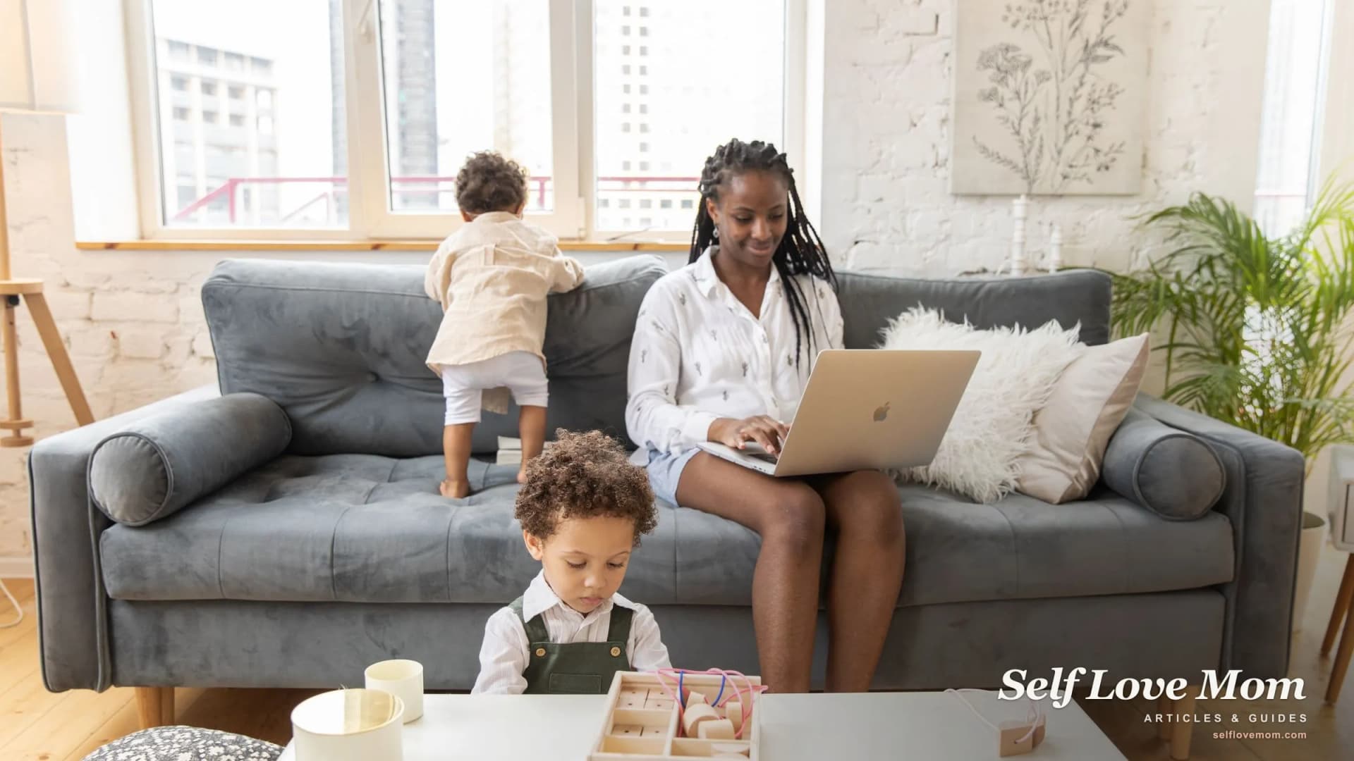 A single mom works on her laptop at home while her two children play nearby, searching for legitimate online jobs.