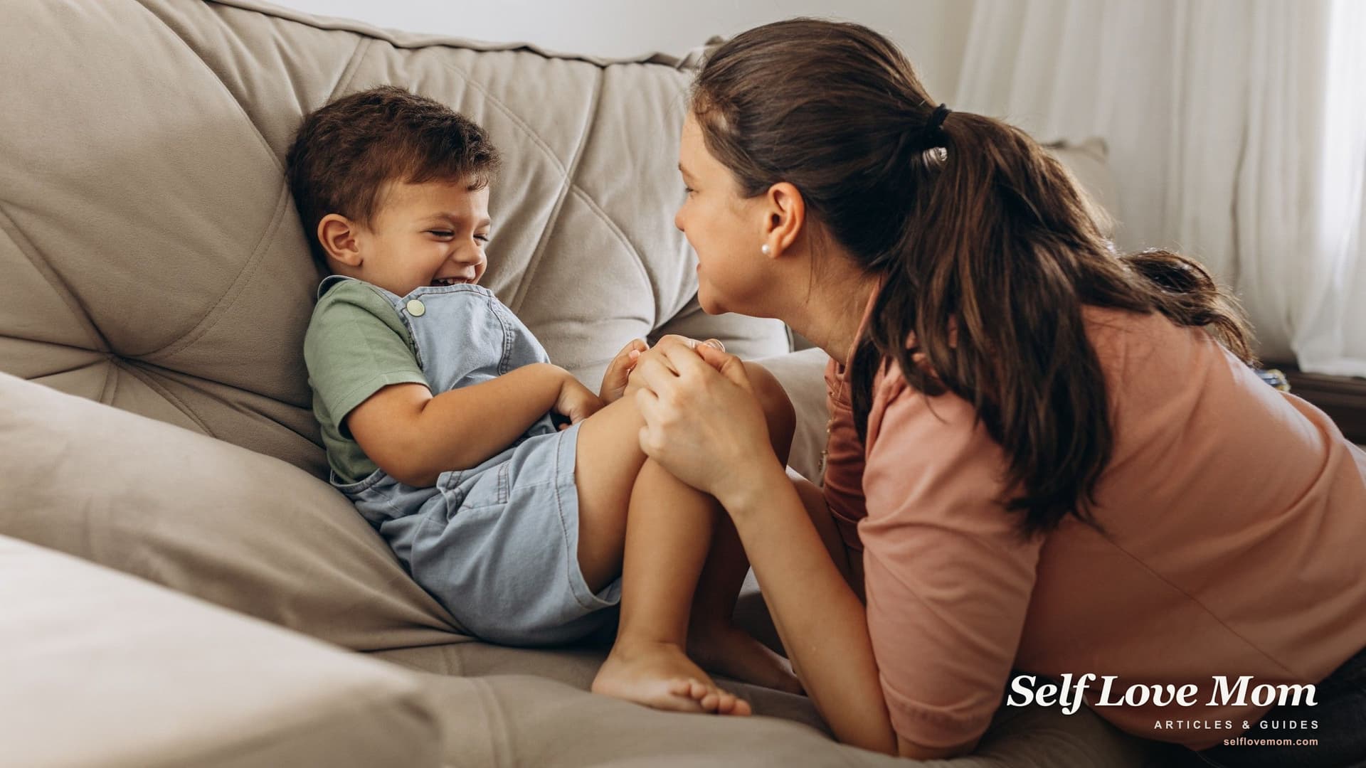 A single mom laughing with her young son on the couch, the full life that makes single motherhood and dating work.