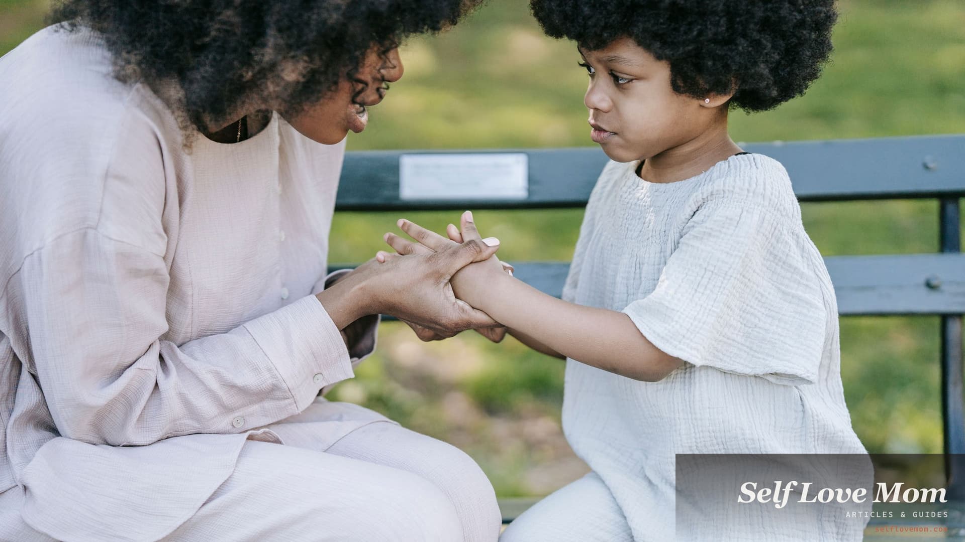 A mother and her young child sit on a park bench holding hands mid conversation, the talk that comes before a new partner moves in