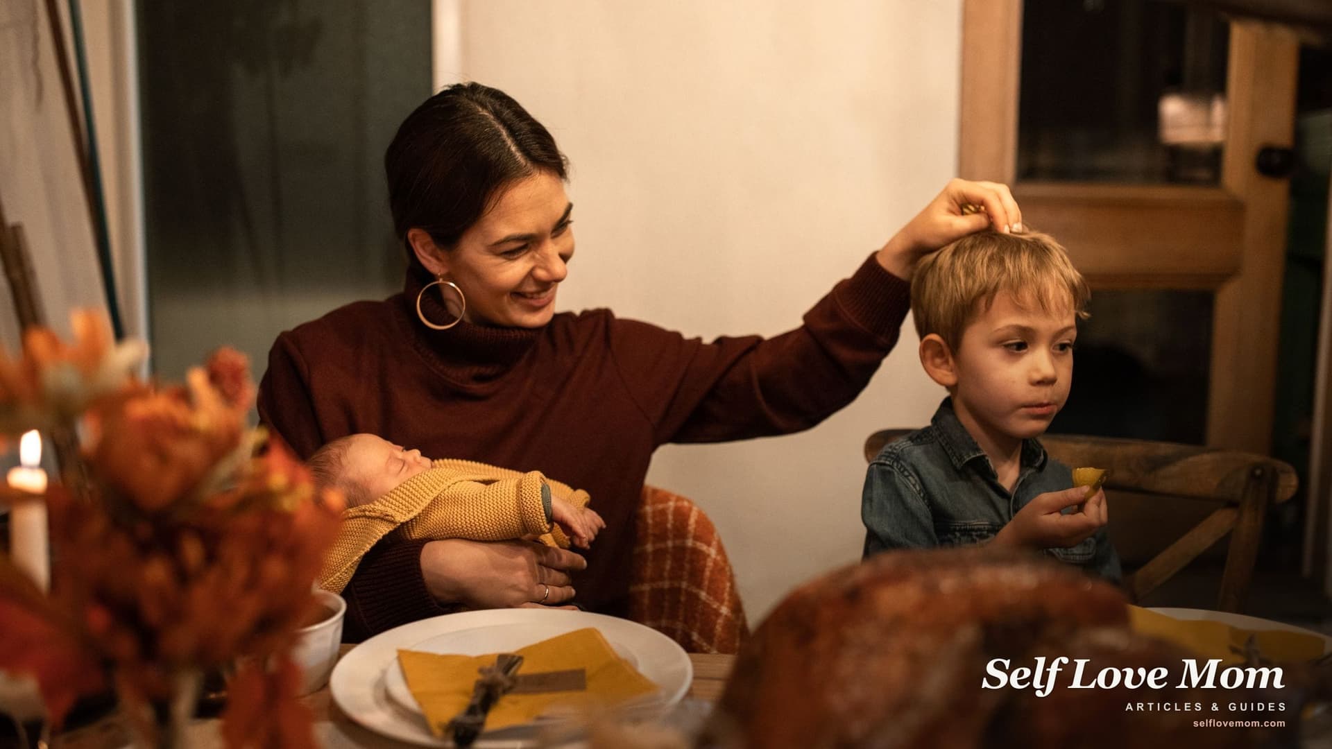 A smiling mother holds her sleeping baby and touches her son's hair at a turkey dinner, the kind of meal free Thanksgiving food programs help single moms serve.