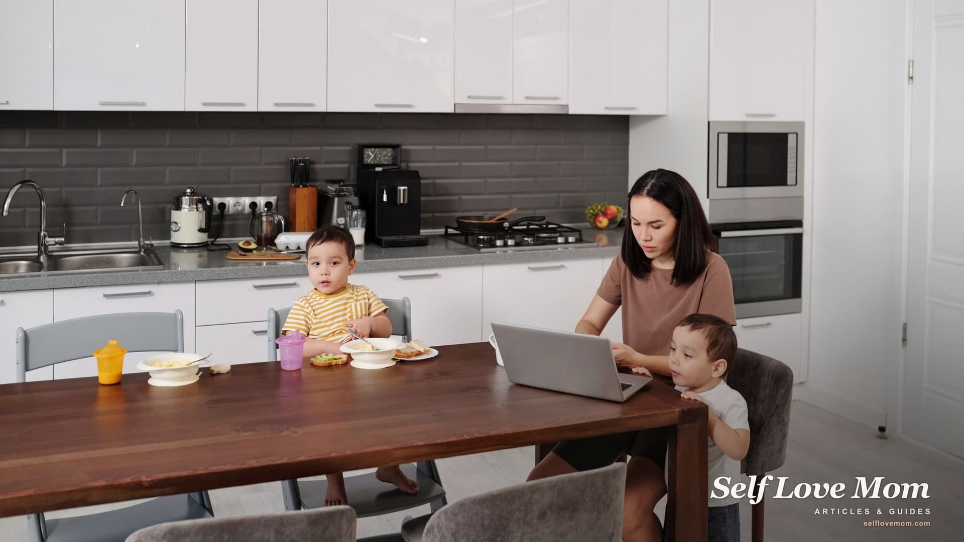 A mother works on her laptop at the kitchen table while her two toddlers eat breakfast, the kind of morning when a Wisconsin single mom applies for help online.