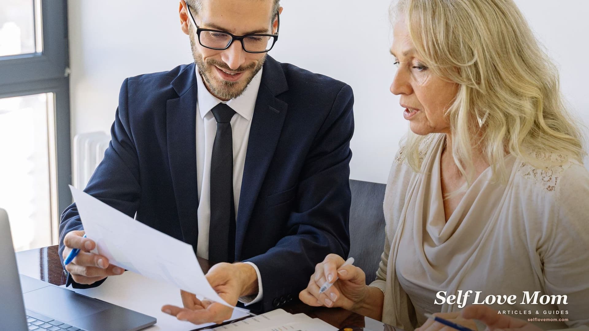 A mother reads through a fee agreement with a family lawyer at his desk, checking the cost of a custody lawyer before she signs.