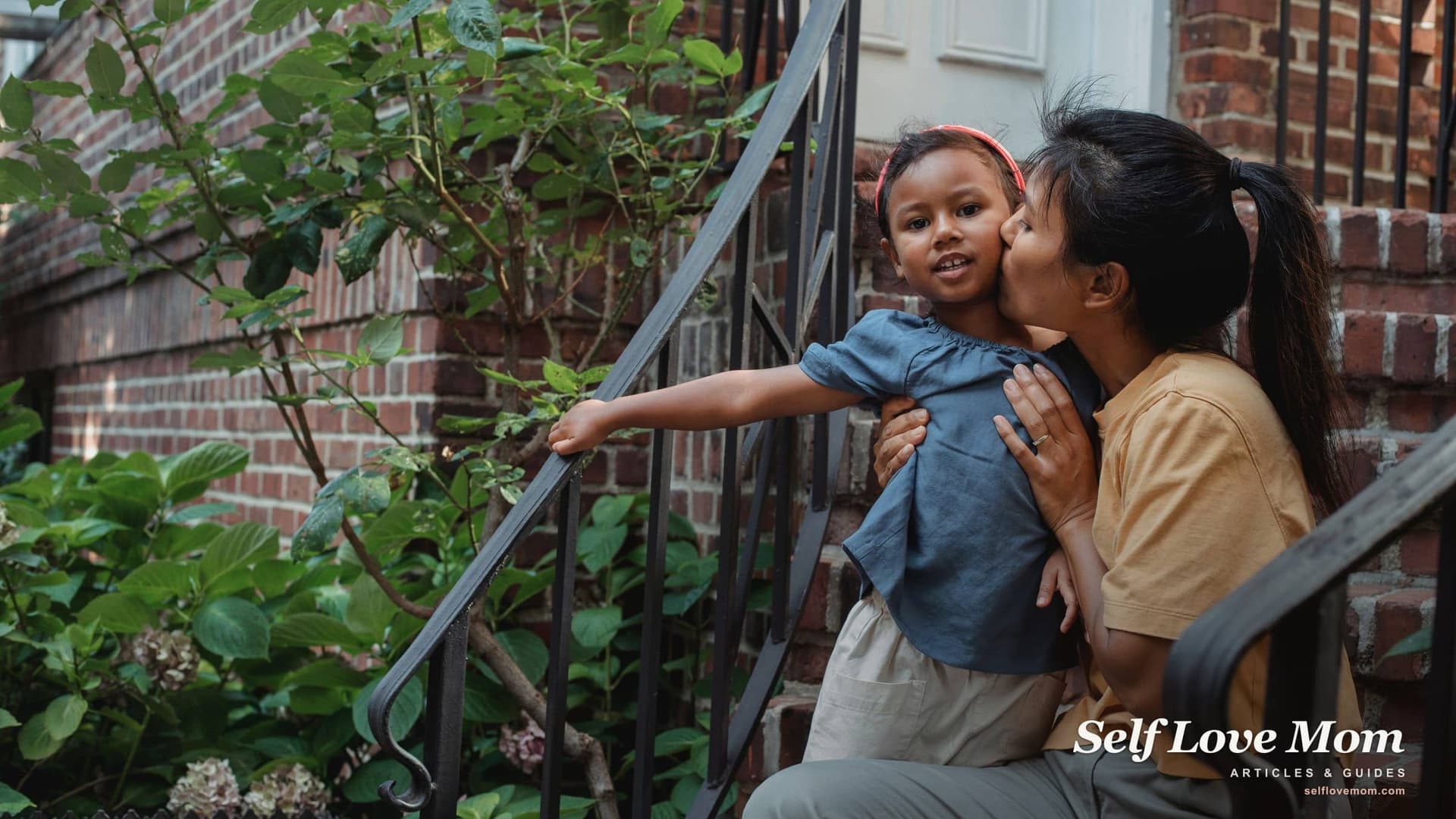 A mother kisses her young daughter on the front steps of their home, the kind of handoff spot a right of first refusal plan often covers.