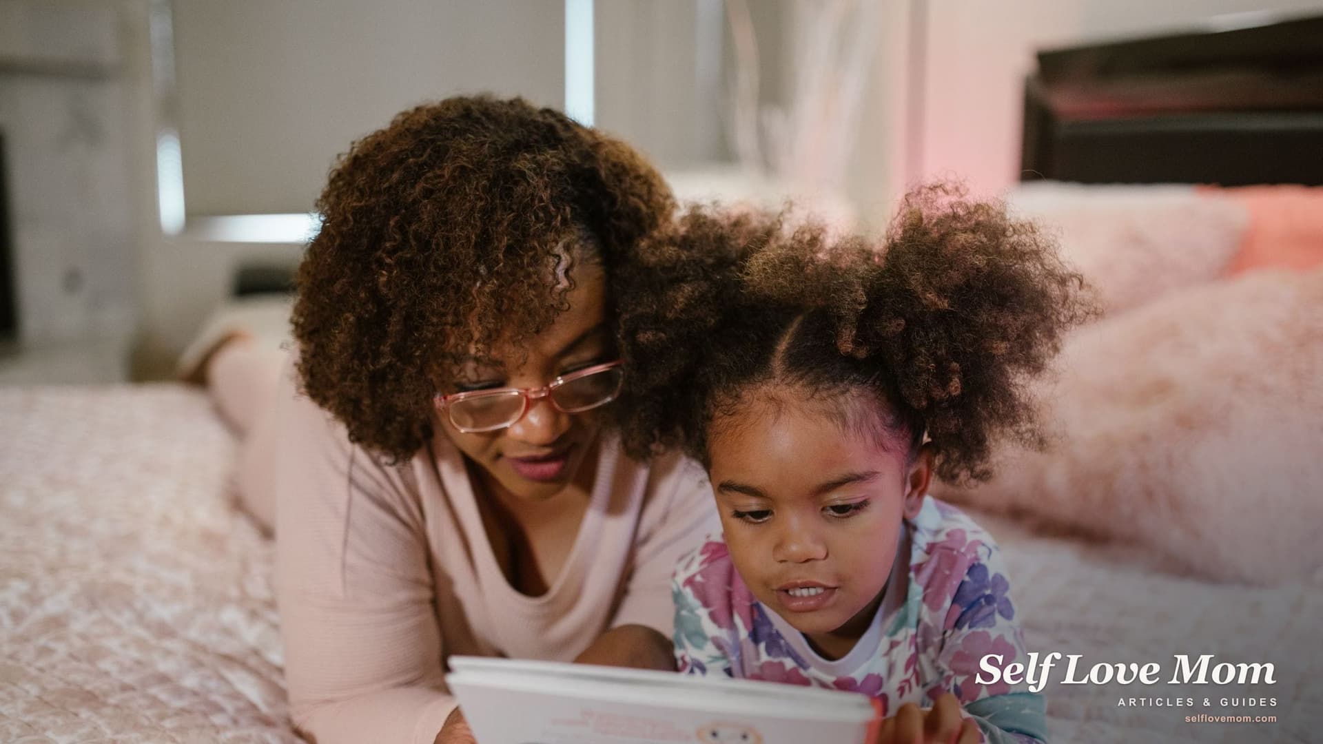 A single mother lies on the bed beside her young daughter, reading a picture book together before bedtime