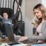 Single mom working from home on her laptop while her child plays, representing the best careers for single moms