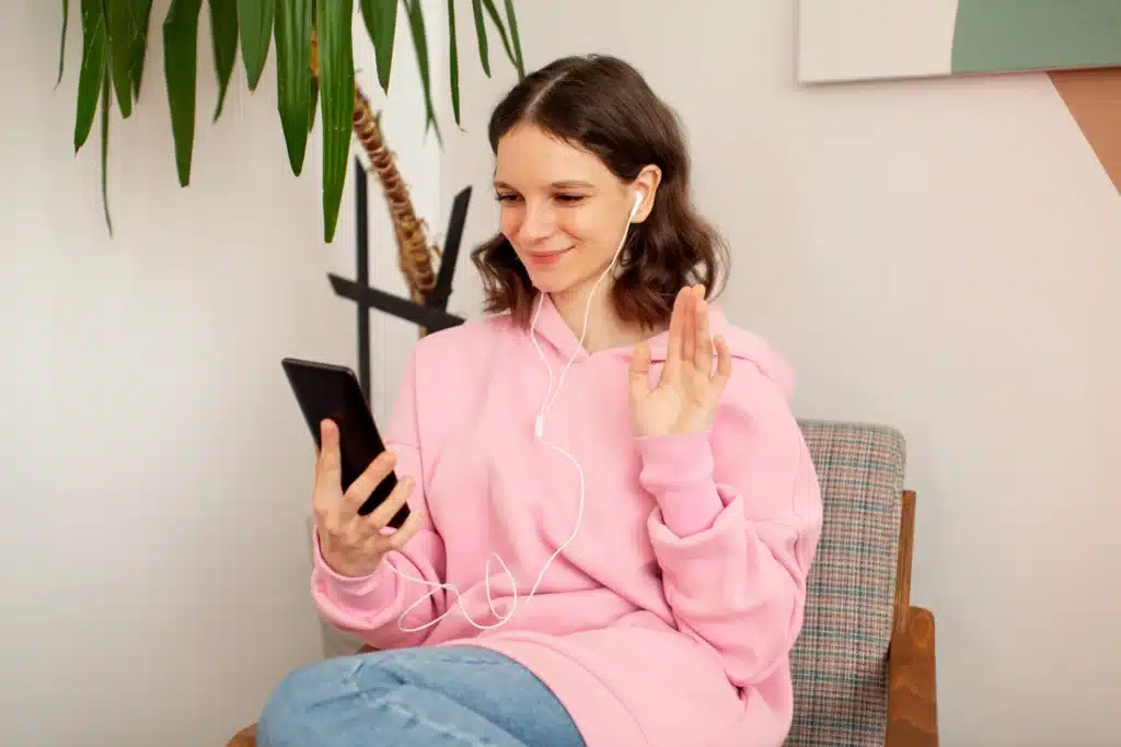 A mom smiling and connecting with a therapy or mental health app on her smartphone, promoting the use of free self care apps for therapy and mental health support.
