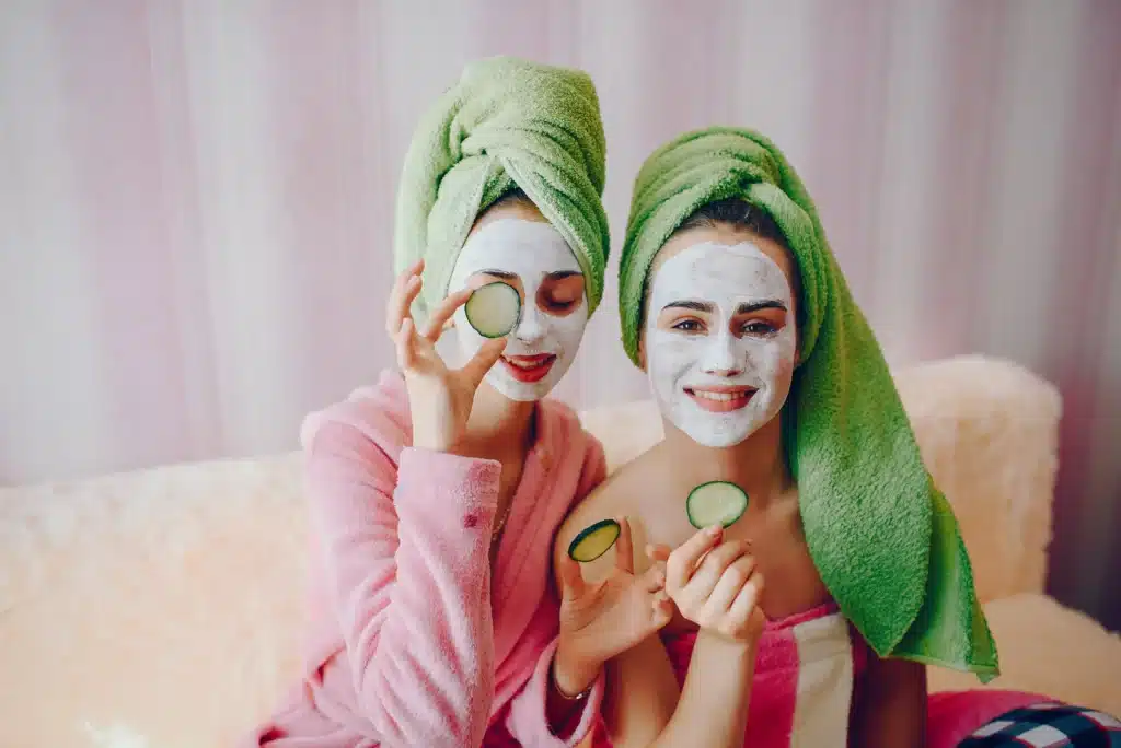 Self care for moms at home – two women with facial masks and cucumbers enjoying a relaxing spa day.