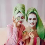 Self care for moms at home – two women with facial masks and cucumbers enjoying a relaxing spa day.