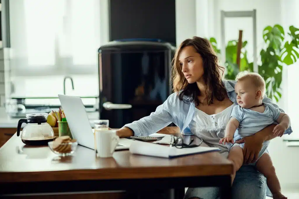 A working mom planning household finances while holding her baby