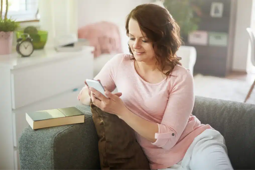 A mom enjoying one of the hobbies for stay at home moms by chatting on her smartphone, staying connected with loved ones.