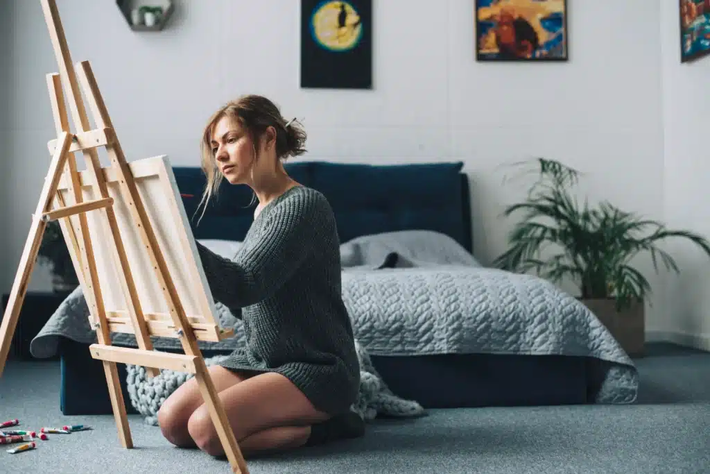 Woman painting on a canvas at home, indulging in a hobby as one of the simple things to do for yourself.