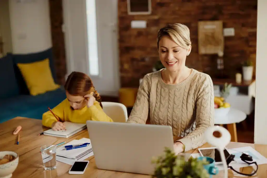 Happy mom working on laptop at home with child – remote jobs for stay at home moms