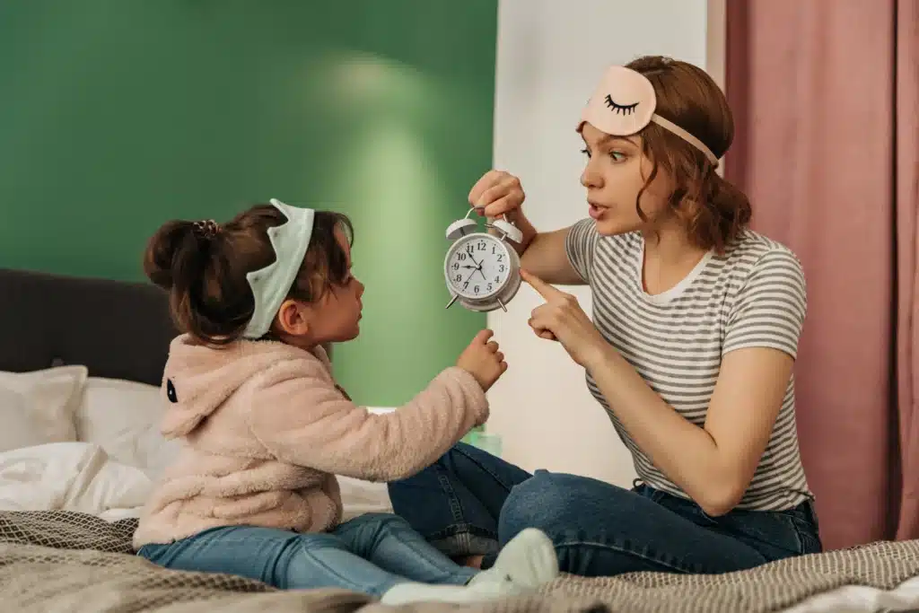 Morning routine for preschoolers as a mom shows the clock to her child, reminding her it's school time.