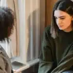 A caring therapist for new moms talking with a new mom during a postpartum counseling session, offering emotional support and understanding.